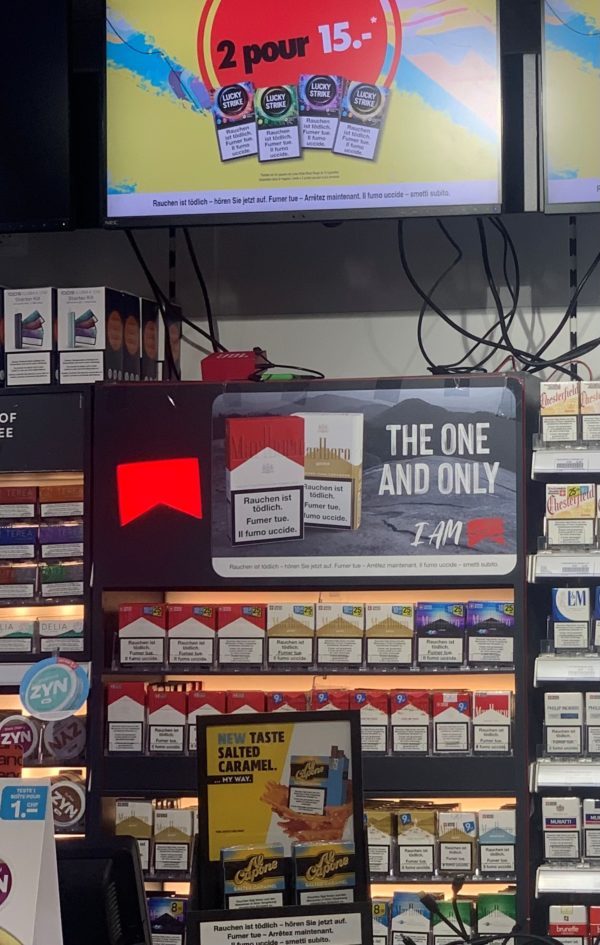 Publicités et promotions pour des cigarettes et cigares dans un kiosque à la gare de Genève, juin 2025